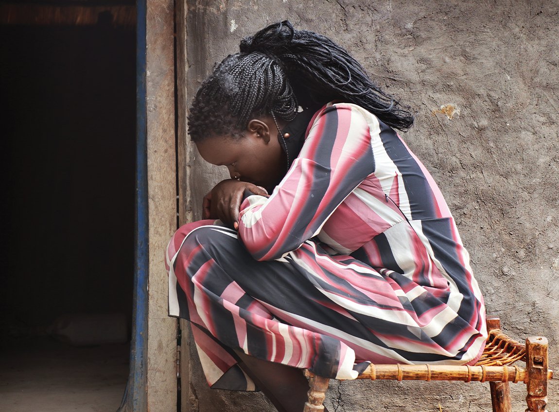 A woman in distress sits hugging her knees to her chest.