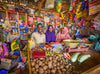 A man and two women smile as they stand inside the store they manage filled with various goods and produce.
