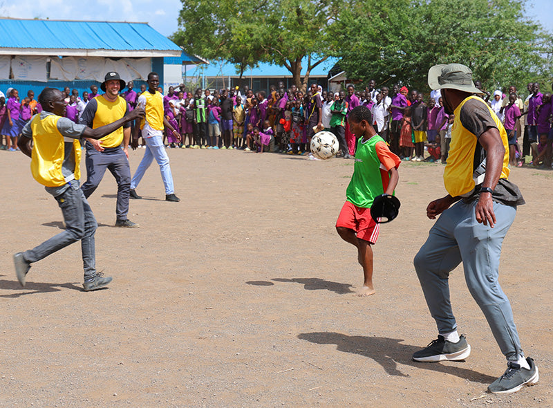 A child plays soccer with members of the CFL.