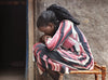 A woman in distress sits hugging her knees to her chest.