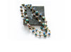 Handcrafted beaded necklace with a mix of round and disc-shaped beads in earthy tones of blue, green, brown, and white, displayed on a dark stone tile against a white background.